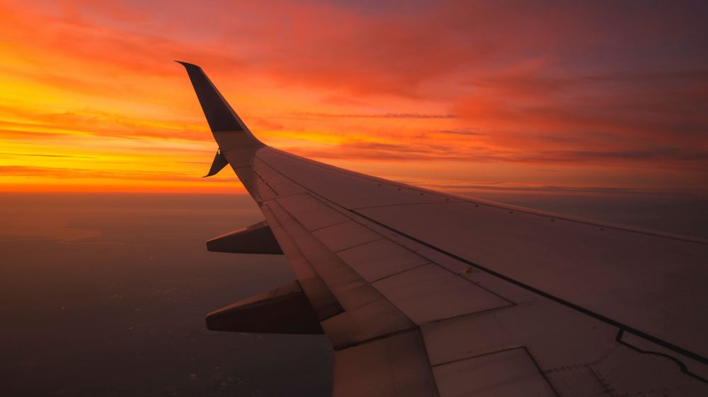 Airplane wing view at sunset during flight